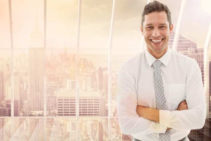 Digital composition of smiling businessman standing with arms crossed against cityscape in background